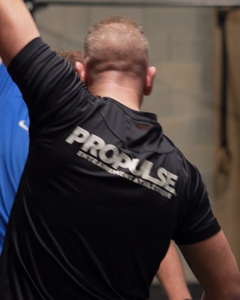 Le dos d'un tee-shirt Propulse pendant que le coach accompagne un mouvement.